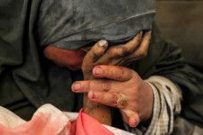 パレスチナ自治区ガザ地区南部ラファで9日、イスラエルの攻撃で殺害された息子の手をとるパレスチナの女性=ロイター
