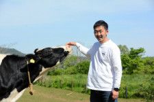 放牧された牛と久保宏輔さん=2024年5月2日午後2時56分、広島市佐伯区、興野優平撮影