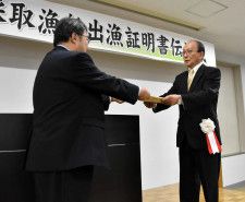 道水産会の山崎副会長（左）から出漁証明書を受け取る小倉組合長