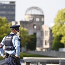 G7広島サミットの開催を前に、平和記念公園で警戒に当たる警察官。奥は原爆ドーム＝16日午後、広島市