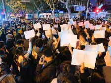 中国上海市中心部で「ゼロコロナ」政策に反対し、当局への抗議を意味する白い紙を掲げる人たち＝2022年11月
