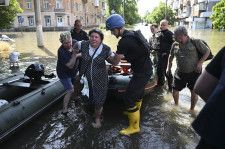 7日、ウクライナ南部ヘルソンで、避難する人たちを助ける当局者ら（ゲッティ＝共同）