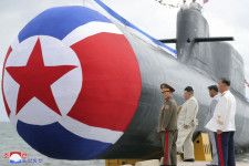 新たに建造された「戦術核攻撃潜水艦」のそばに立つ北朝鮮の金正恩朝鮮労働党総書記（左から2人目）＝6日（朝鮮中央通信＝共同）