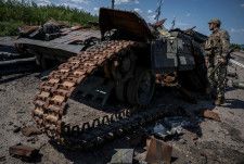 ウクライナ南部ザポロジエ州のロボティネ近くで、破壊されたウクライナ軍戦車を見るウクライナ兵＝8月（ロイター＝共同）