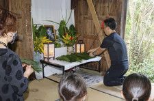 「一村忌」で祭壇にソテツの葉を供える参加者＝10日、鹿児島県奄美市
