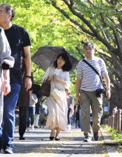 東京・明治神宮外苑のイチョウ並木を日傘を差して歩く人＝4日午後1時36分