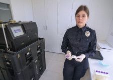 DNA鑑定装置とウクライナ国家警察のボイテンコ少佐＝6日、キーウ（共同）