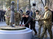 ウクライナ・キーウのホロドモール博物館で、やせ細った少女の像にろうそくを供えるゼレンスキー大統領夫妻（中央）＝25日（共同）