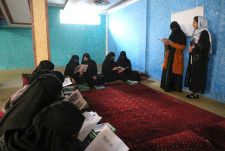 アフガニスタンの首都カブールの「地下学校」で中村哲さんを題材にした絵本を読む女子生徒ら＝11月（共同）