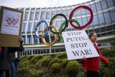 国際オリンピック委員会本部の前でロシアとベラルーシ選手の中立での参加判断に抗議するウクライナ支援団体のメンバーら＝2023年3月、ローザンヌ（Keystone提供・AP＝共同）