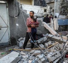 イスラエル軍の攻撃を受けたガザ地区南部ラファの建物近くで少女を抱くパレスチナ人男性＝8日（ゲッティ＝共同）