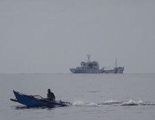 スカボロー礁付近で漁をするフィリピン人漁師（手前）と周辺を監視する中国公船＝2016年12月