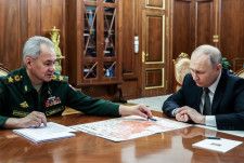 20日、モスクワの大統領府でショイグ国防相（左）と会談するロシアのプーチン大統領（ロシア大統領府提供・タス＝共同）