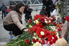 23日、銃乱射があったモスクワ郊外の「クロッカス・シティ・ホール」で、犠牲者を悼む花を手向ける人（ゲッティ＝共同）