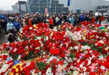 24日、モスクワ郊外クラスノゴルスクで、銃乱射テロの現場近くに追悼の花を手向ける市民ら（タス＝共同）