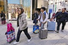 東京・銀座でスーツケースを手に歩く外国人ら＝1月
