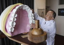 インプラントの模型を見せる「歯ART美術館」の飯間昇館長＝2024年3月25日、高松市庵治町