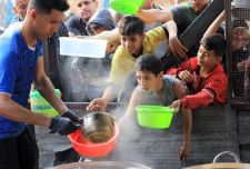 食料配給を求めて容器を差し出す人々＝3月30日、ガザ地区南部ラファ（ゲッティ＝共同）