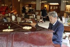 新潟市の岩室温泉にある旅館「穂々」でピアノを演奏する坪田圭司さん＝新潟市、2024年3月