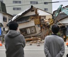 解体される家を見つめる住民の大田宏さん（右）ら＝8日午前、石川県穴水町