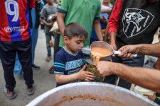 支援団体から食事の配給を受け取る子ども＝1日、パレスチナ自治区ガザ中部デールバラハ（ゲッティ＝共同）