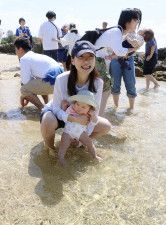 海開きされた鹿児島県・奄美大島の浜辺で、赤ちゃんの足を海水に浸す保護者＝11日午前