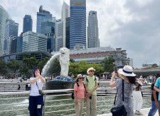 シンガポールのマーライオン像の前で写真撮影する中国人観光客ら＝2024年3月（共同）