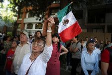 6日、メキシコの首都メキシコ市のエクアドル大使館前で抗議する人たち（ロイター＝共同）