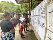 17日、ソロモン諸島ホニアラで総選挙の立候補者を見る有権者ら（共同）