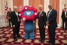 ロンドンの日本大使館で大阪・関西万博の公式キャラクター「ミャクミャク」と共に並ぶ林肇駐英大使（右から2人目）ら＝16日（共同）