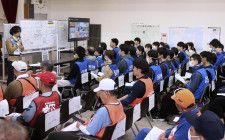 石川県七尾市のボランティアセンターで、一般のボランティア（手前）とともに活動の説明を受ける県職員ら（奥）。本年度の新規採用職員も研修として参加した＝17日午前