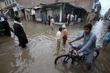 パキスタン北西部ペシャワルで冠水した道路を歩く人々＝15日（AP＝共同）