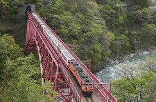 一部区間で運行を再開し、鉄橋を渡る黒部峡谷鉄道のトロッコ電車＝19日午前、富山県黒部市