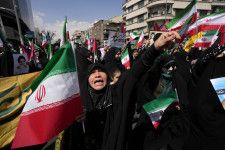 19日、テヘランで、イラン国旗を掲げながら反イスラエル集会に参加した人々（AP＝共同）