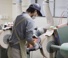 「オホーツク楽器工業」でエレキギターのボディーを研磨する職人＝北海道西興部村（2024年4月）