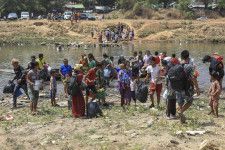 20日、ミャンマー側から国境を流れる川を渡ってタイ北西部メソトに避難してくる人たち（AP＝共同）