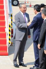 21日、カンボジア・プノンペンの空港で関係者と握手を交わす中国の王毅外相（共同）