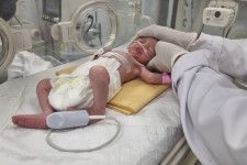 イスラエル軍の攻撃により死亡した妊婦から生まれ、病院の保育器に横たわる女児＝21日、ガザ地区南部ラファ（AP＝共同）