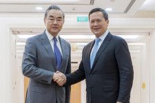 中国の王毅外相（左）と握手するカンボジアのフン・マネット首相＝22日、プノンペン（クメール通信提供、AP＝共同）