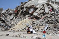 パレスチナ自治区ガザ北部でイスラエルの空爆により破壊された住宅の近くに座る少年＝22日（ロイター＝共同）