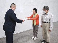 北陸電力本店を訪れ、担当者（左）に議案を手渡す市民団体のメンバーら＝25日午後、富山市