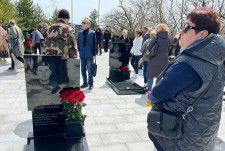 ウクライナ侵攻で戦死した息子ニキータ・リャミンさんの墓の前に立つ母マリーナさん（右端）＝25日、ロシア・ウラジオストク（共同）