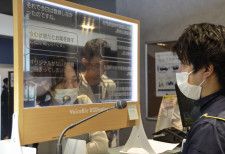 透明ディスプレーを使ってコミュニケーションを取る外国人観光客（左）＝26日午後、北海道千歳市
