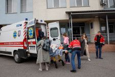 26日、ウクライナ・キーウの病院から子どもを避難させる人たち（ロイター＝共同）