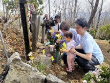 日航ジャンボ機墜落事故で亡くなった父孝之さんの墓標に語りかける小沢秀明さん（右手前）ら＝29日、群馬県上野村