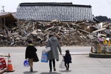 避難所で配られた支援物資を手に歩く親子連れ＝3月、石川県珠洲市宝立町地区