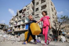 イスラエル軍の攻撃で破壊された建物近くを歩く子どもたち＝1日、ガザ地区南部ラファ（ロイター＝共同）