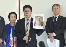 羽田空港で、横田早紀江さんの写真を手にして取材に応じる拉致被害者家族会代表の拓也さん（中央）。右は事務局長の飯塚耕一郎さん＝4日午後