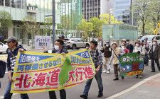 原発の再稼働反対などを訴える横断幕を手に行進する参加者＝5日午後、札幌市