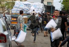 6日、イスラエル軍がパレスチナ自治区ガザ南部ラファからの退避を要求後、小麦粉の袋をつかむ住民たち（ロイター＝共同）